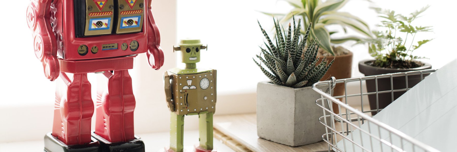 A small green robot, overlooking some paperwork, perhaps about to file a FOIA request. Cut off is a larger red robot standing next to it, perhaps getting ready to file a FOIA appeal.