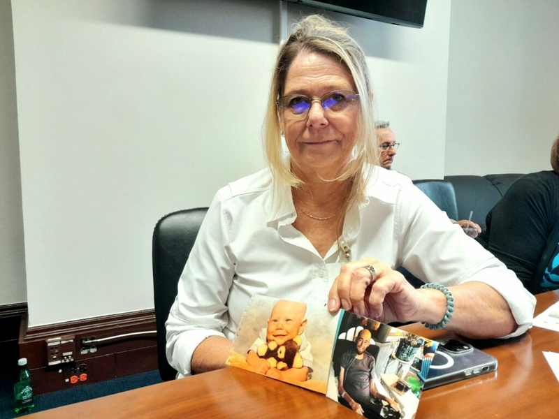 Tammy Tesson Puhlmann, 63, who now lives in Villa Ridge, Missouri, shows photos of her son Drew as she sat in the Russell Senate Office Building on May 22, 2024. Puhlmann’s son died of cancer at age 30, and she was among 10 eastern Missouri residents speaking to lawmakers on Capitol Hill about expanding the Radiation Exposure Compensation Act. (Ashley Murray/States Newsroom)